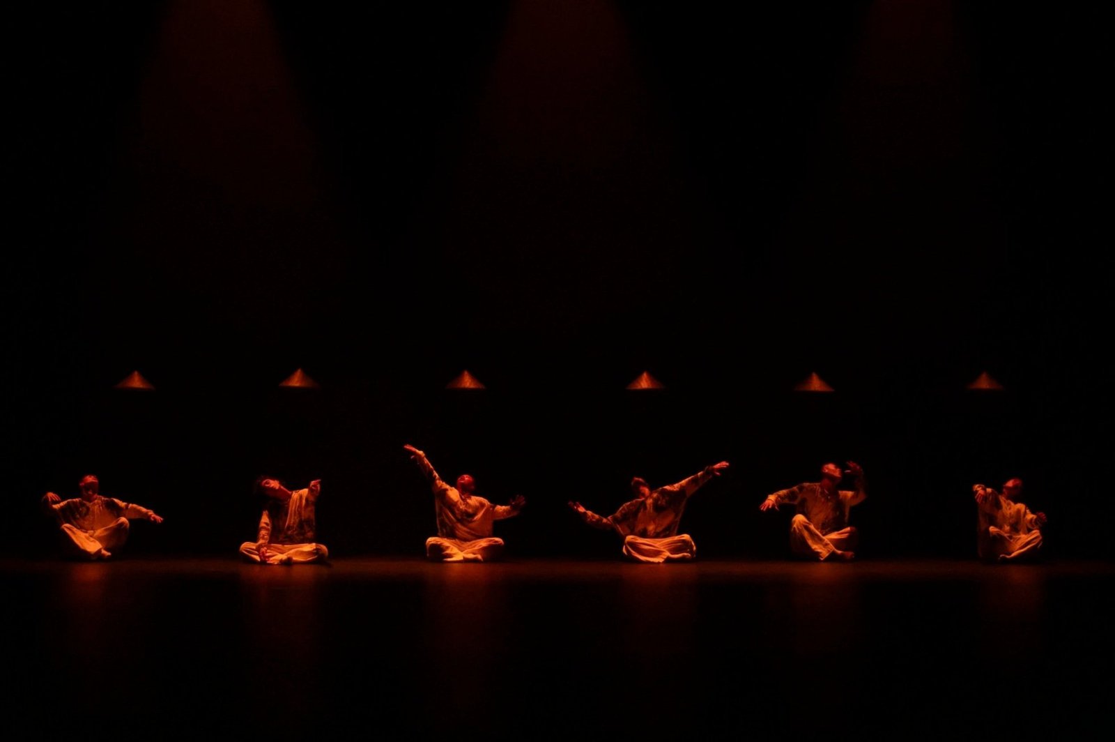 El elenco de Vortex sentado en escena bajo una iluminación ámbar
