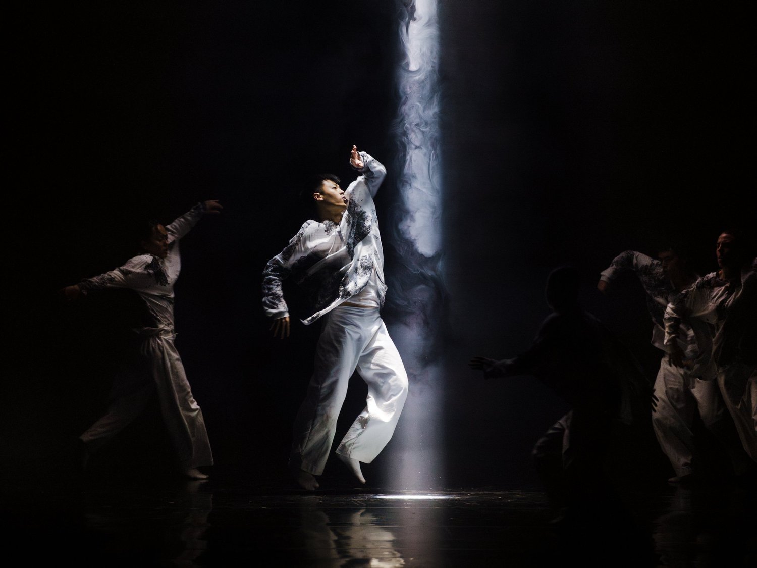 Un intérprete de Vortex bajo un haz de luz, rodeado por los bailarines de HUMANHOOD
